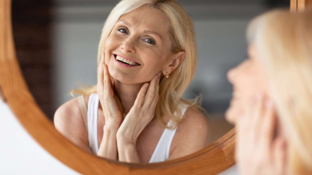 Happy woman admiring her skin results from consistent anti-aging skincare routine