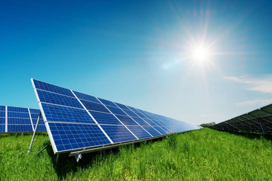 Large-scale DIY solar panel array installation on green field under bright sunny sky with sun rays