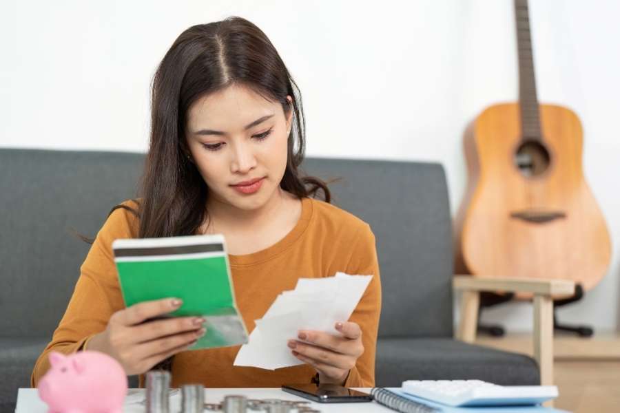 Young Asian woman reviewing finances and documents for single parent financial planning at home