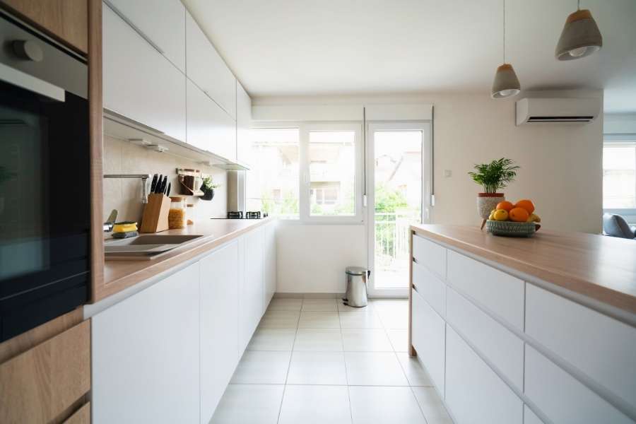 A bright and modern calming minimalist kitchen with white cabinets and a wooden island.